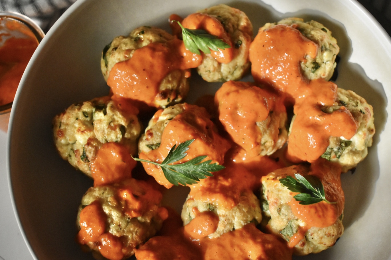 chicken meatballs with roasted red pepper sauce, topped with parsley