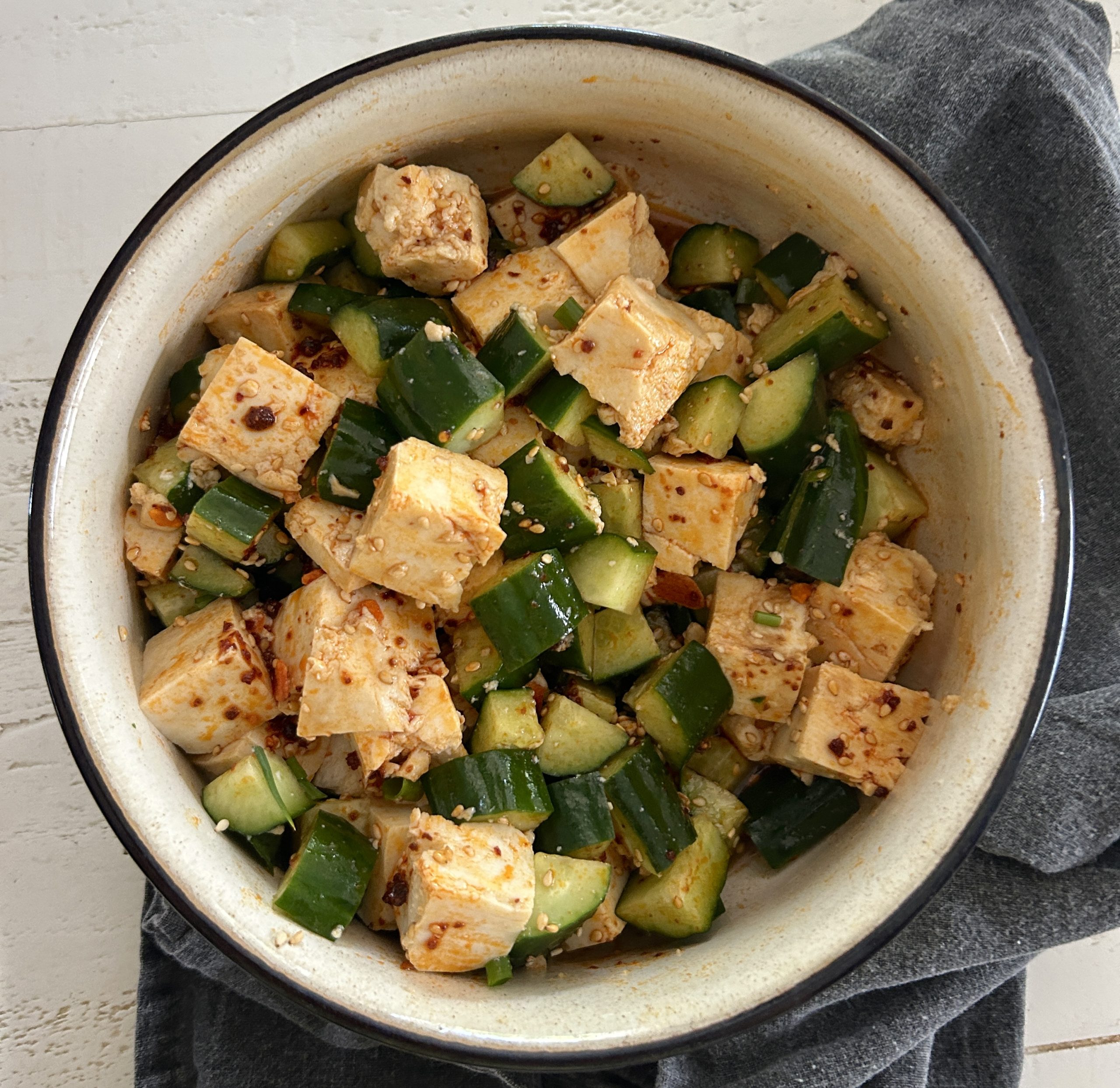 An easy spicy, Asian-style cucumber salad recipe with soft tofu, cucumbers, chili crisp/chili crunch, sesame seeds